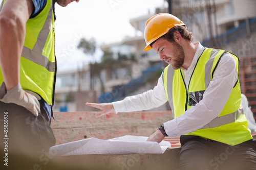 Construction worker engineer reviewing blueprints at highrise construction site
