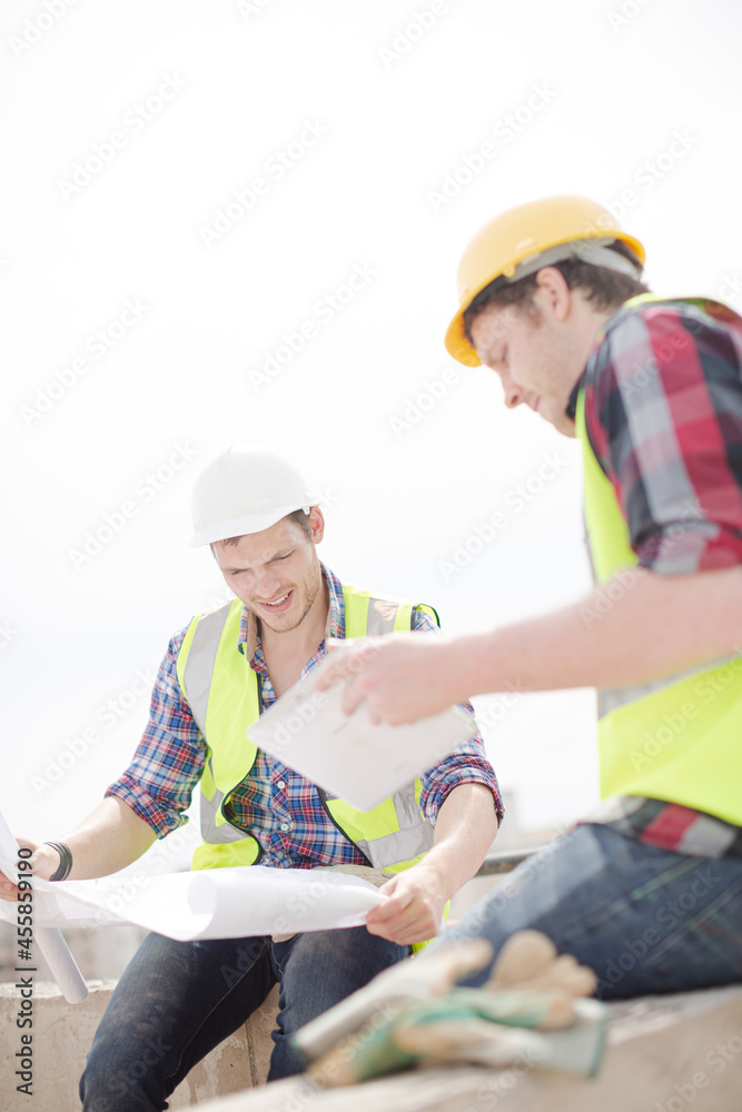 Construction worker engineer reviewing blueprints at highrise construction site Construction worker engineer reviewing blueprints at highrise construction site