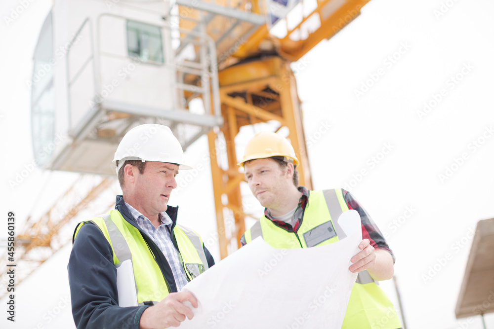 Construction worker engineer reviewing blueprints at highrise construction site Construction worker engineer reviewing blueprints at highrise construction site