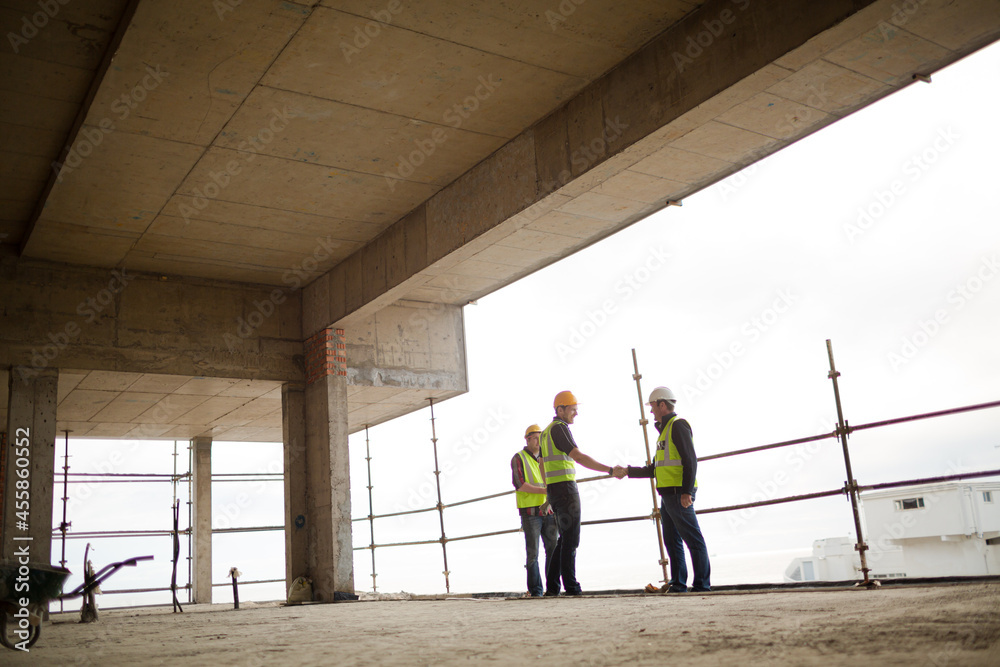Construction workers handshaking at highrise construction site
