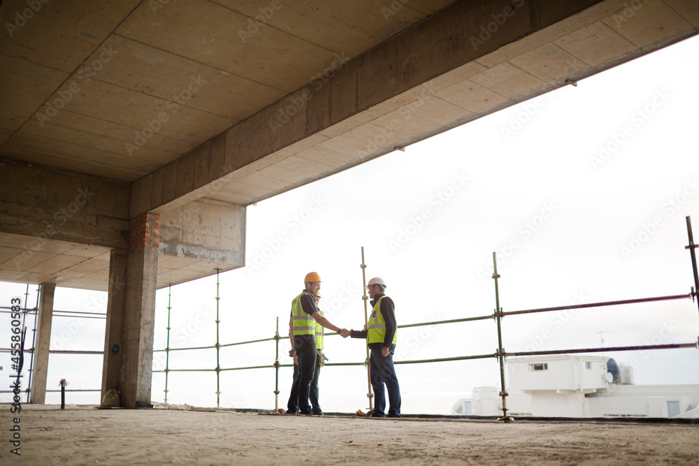 Construction workers handshaking at highrise construction site