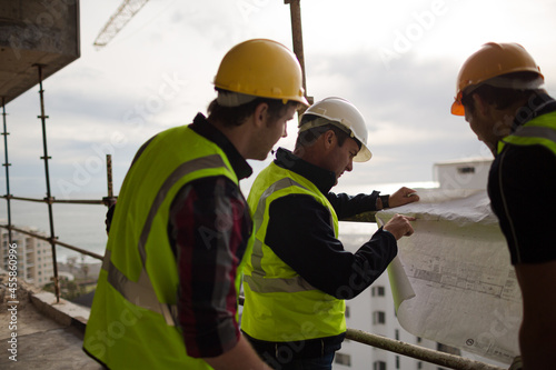 Construction worker engineer reviewing blueprints at highrise construction site