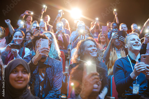 Eager audience with smart phone flashlights in dark auditorium © KOTO