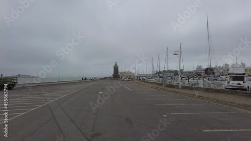 Driving POV across parking lot to Marina District Lighthouse with boats.
