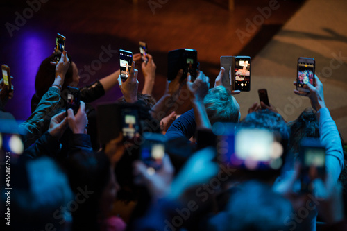 Audience with smart phones videoing conference