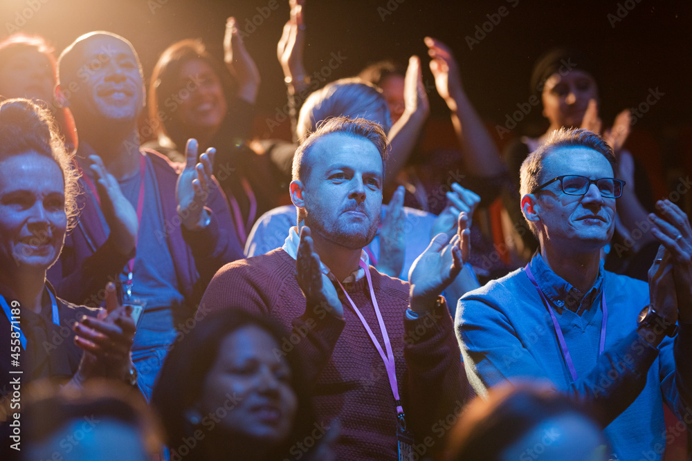Excited audience clapping in dark room