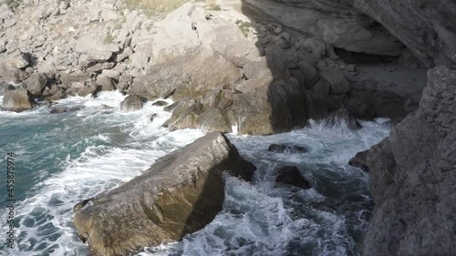 Water splashing. Pirate Bay Novy Svet Places. Mount Eagle is an ancient coral reef. Crimea. Sea water beats against rocks. Sea waves of blue-gray water beat against the coastal rocks.