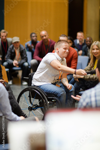 Audience watching male speaker in wheelchair talking on stage