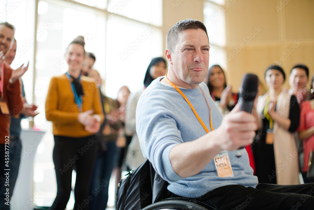 Audience watching male speaker in wheelchair talking on stage Audience watching male speaker in wheelchair talking on stage