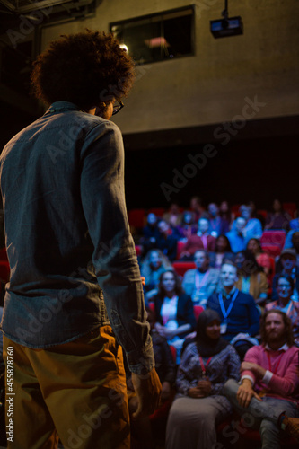 Male speaker on stage talking to audience © KOTO