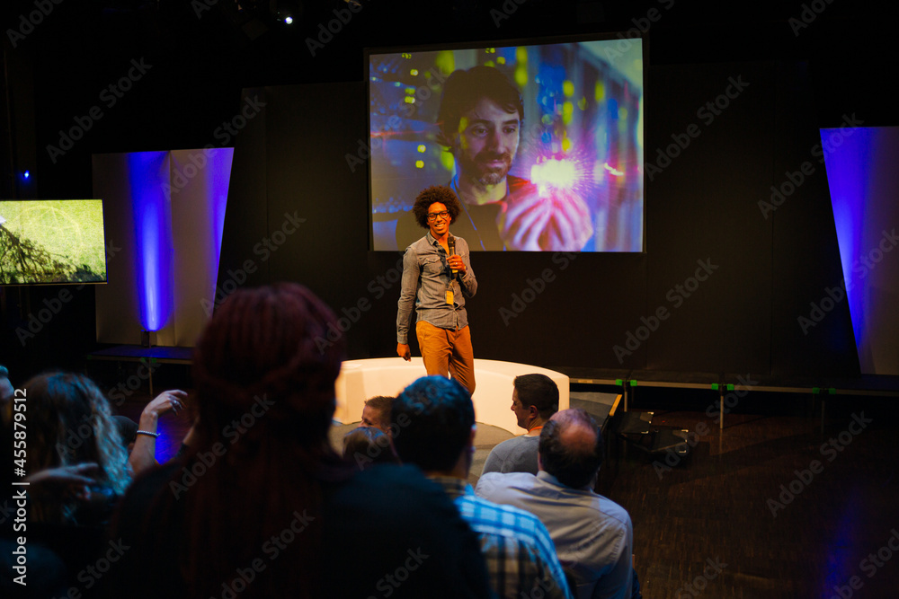 Male speaker with microphone talking to audience Male speaker with microphone talking to audience