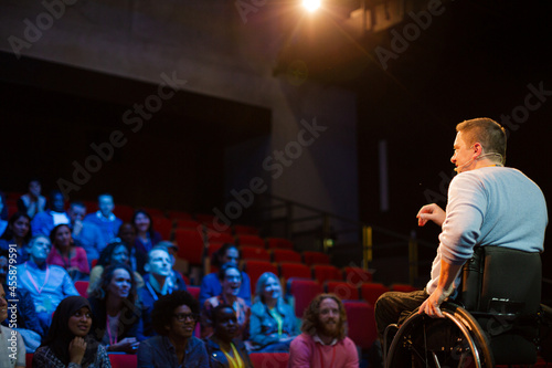 Speaker in wheelchair on stage talking to conference audience