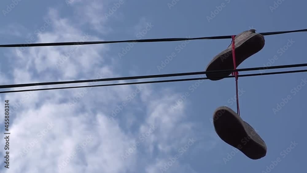 Old boots hanging on an electric wire shoes hanging from some light cables as a tradition in the street during the day. Old boots hanging on an electric wire shoes hanging from some light cables as a tradition in the street during the day.