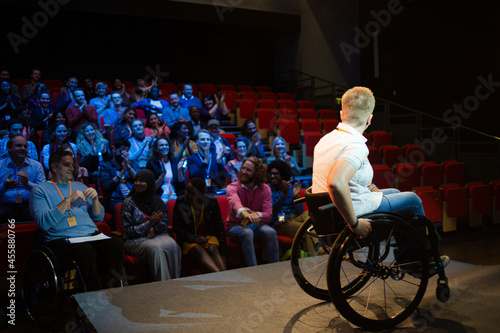 Smiling female speaker in wheelchair on stage