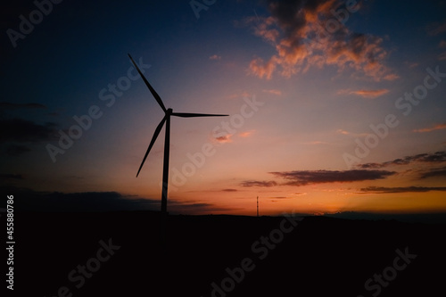 Windmill silhouette at sunset sky. Wind turbine generator