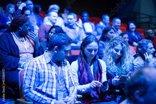 Man and woman with smart phone in conference audience