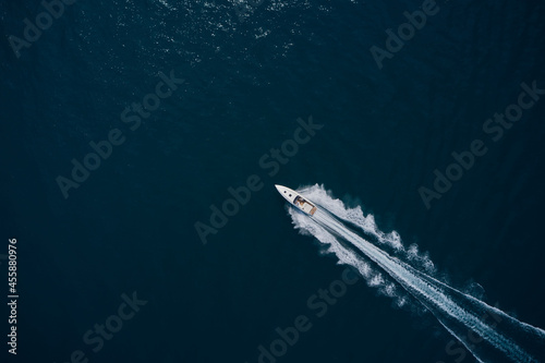 Speedboat wave speed water. Speed boat faster movement on the water top view. Speedboat movement on the water. Large white boat driving on dark water. Speedboat on dark blue water aerial view. © Berg