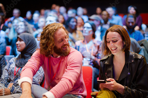 Man and woman with with smart phone in conference audience