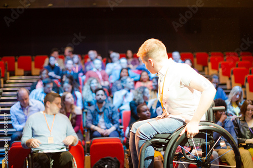 Audience watching female speaker in wheelchair on stage