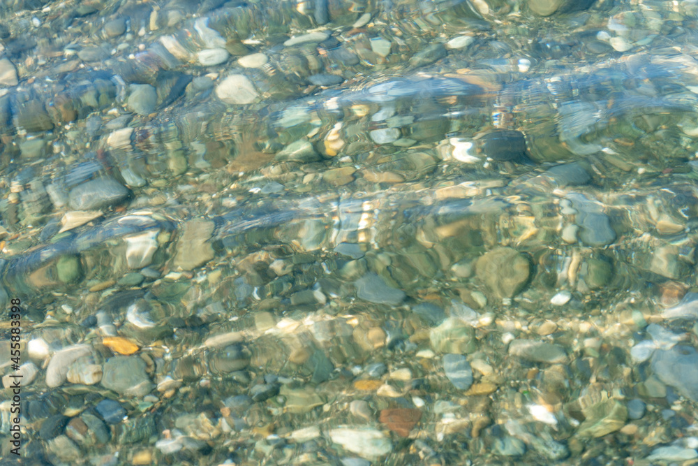 Background of wet pebbles on the bottom of the sea, which is washed by a sea wave Background of wet pebbles on the bottom of the sea, which is washed by a sea wave