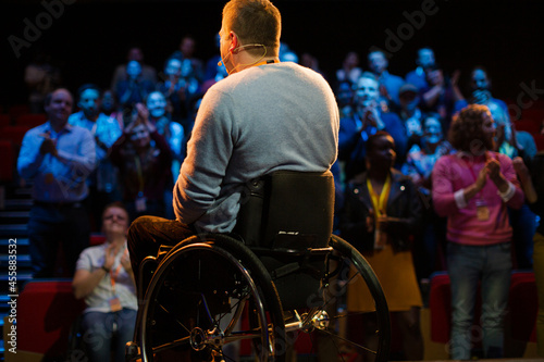 Speaker in wheelchair on stage talking to conference audience