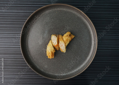 deep fried golden long fish paste wrapped in beancurd skin lobar wuxiang on dark grey wood background dim sum halal menu photo