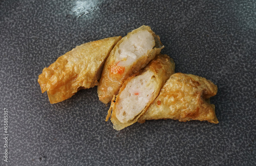 deep fried golden long fish paste wrapped in beancurd skin lobar wuxiang on dark grey wood background dim sum halal menu