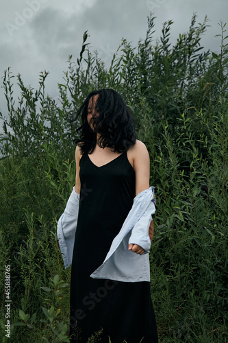 Dreamy portrait of woman in summer park outdoors. Close up, brunette young lady in black dress and blouse. Summer fashion and beauty.