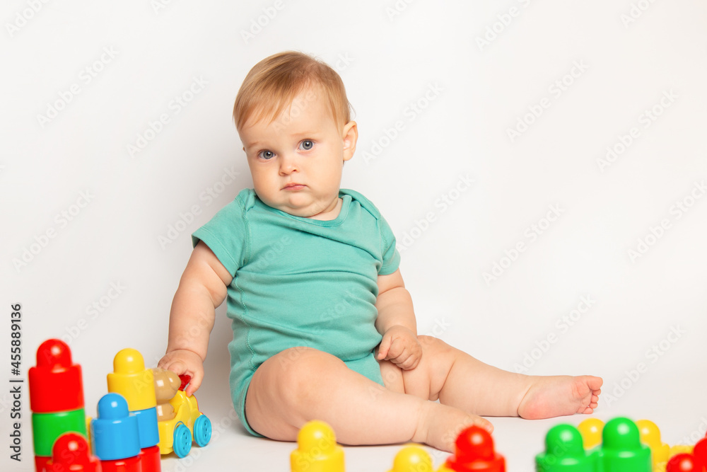 Obraz premium Kid playing with colorful educational constructor blocks. Little boy with creative toys. games for young children. Baby on white background. development of fine motor skills of children concept