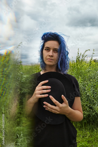 Attractive woman with flying blue hair and closed eyes. Close up dreamy portrait young lady with black hat. Concept of freedom, well being and lifestyle