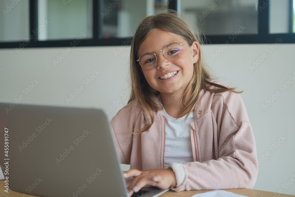 young girl with glasses working on laptop doing her lessons at home young girl with glasses working on laptop doing her lessons at home