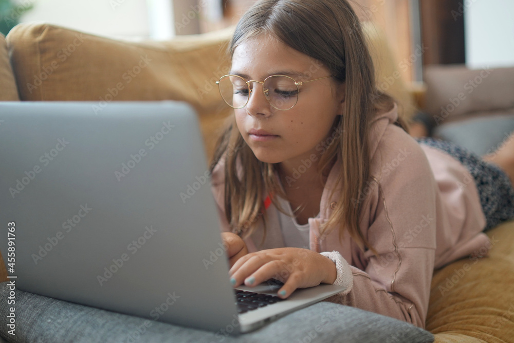 young girl with glasses on laptop in home sofa young girl with glasses on laptop in home sofa