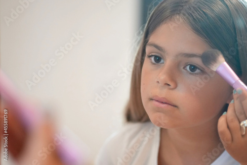 young girl applying makeup in front of a mirror