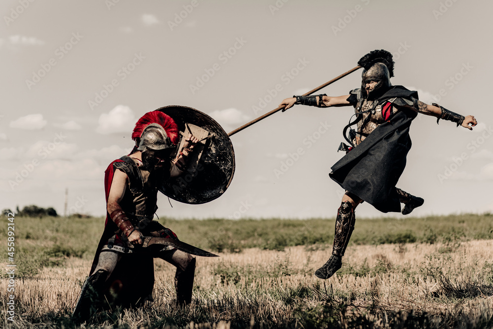 Battle with spear and sword between two ancient warriors in battle dress on meadow. - obrazy, fototapety, plakaty 