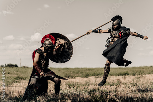 Battle with spear and sword between two ancient warriors in battle dress on meadow. photo