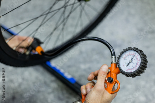 Cropped shot of professional mechanic working in bicycle repair shop. A worker pumps up the tires with a pump.