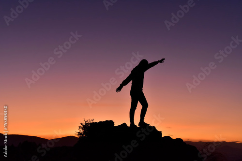 A man standing on the rock with open hands and enjoying to watch sunset.