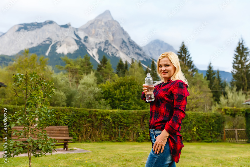 Fototapeta premium Alps. A woman drinking water from a bottle and admiring the mountain scenery.