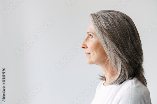 Grey senior woman in t-shirt looking aside while posing in profile photo