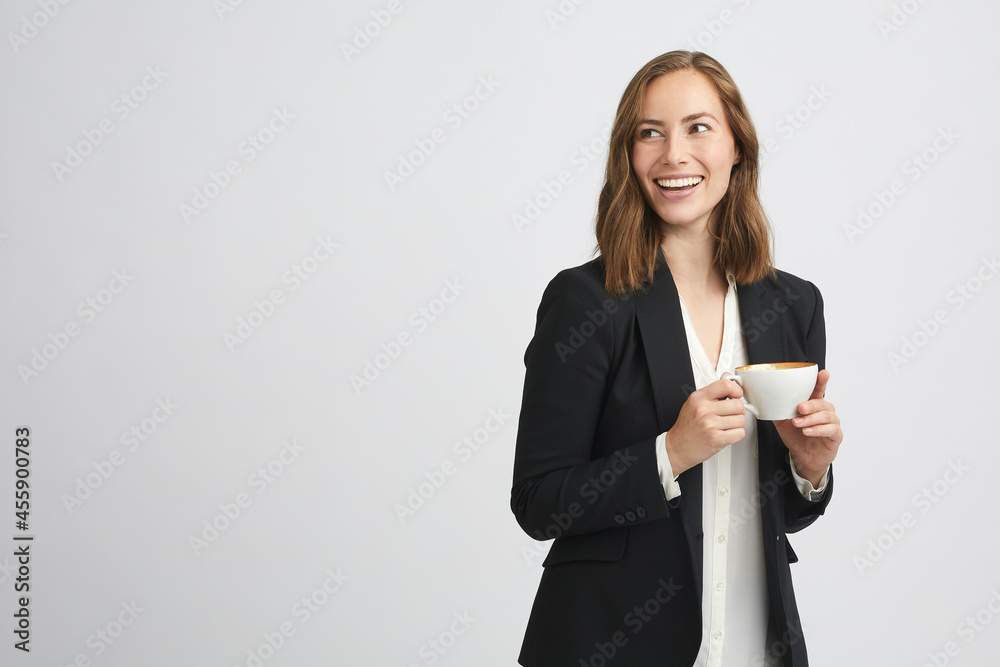 Portrait of a young happy business woman or girl holding a cup of coffee while looking to the left side Portrait of a young happy business woman or girl holding a cup of coffee while looking to the left side