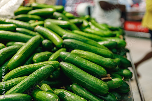 Pile of fresh cucumbers on counter in supermarket