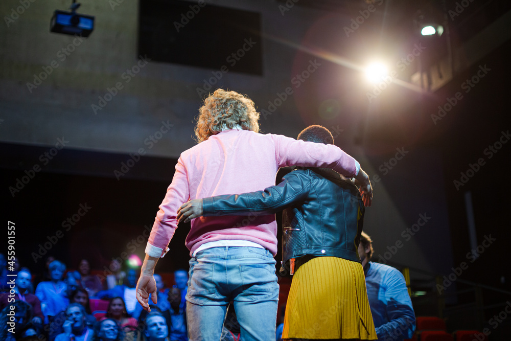 Speakers hugging on stage for audience at conference