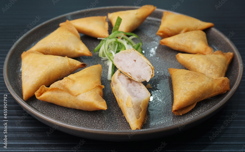 deep fried crispy yam taro spring roll samosa on dark grey wood