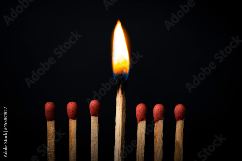 Burning match on dark black background. Difference and uniqueness concept.