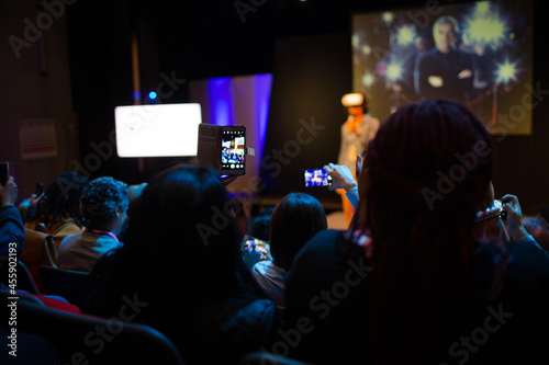 Eager audience with smart phone flashlights in dark auditorium