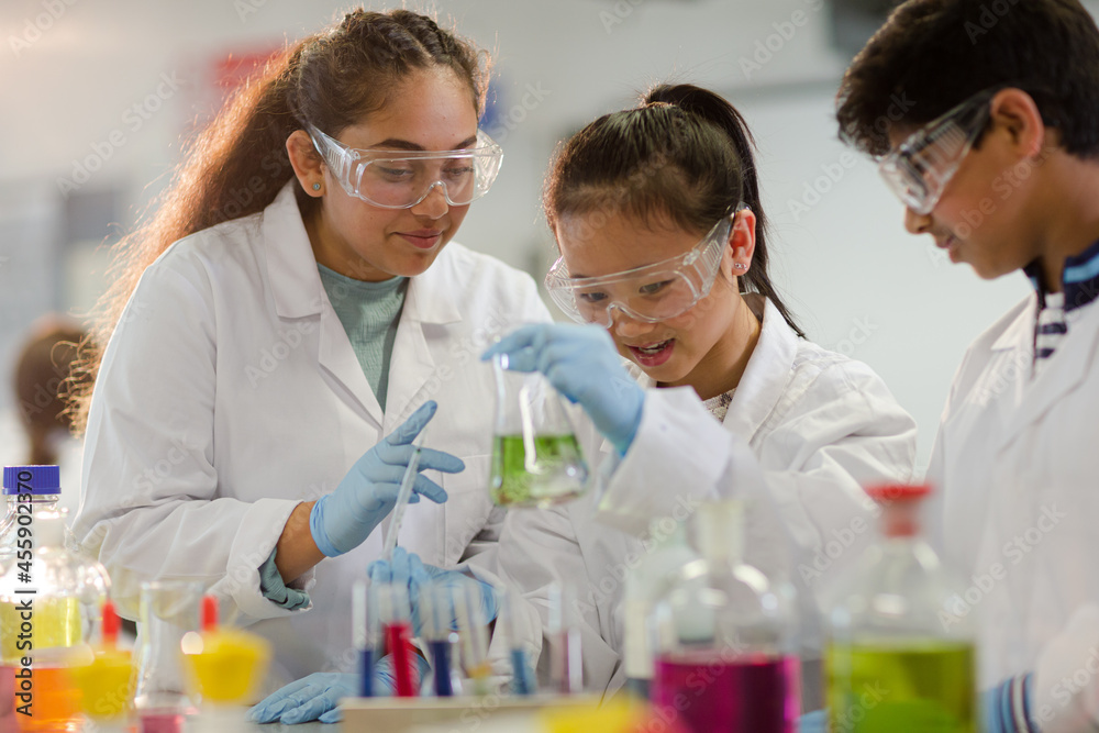 Students watching chemical reaction, conducting scientific experiment in laboratory classroom