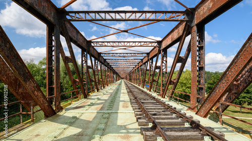 Old railway line crossing a rusty bridge turned into recreational track for rail-cycle draisine with four wheels. photo