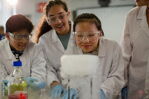 Female teacher and students watching scientific experiment chemical reaction in laboratory classroom photo