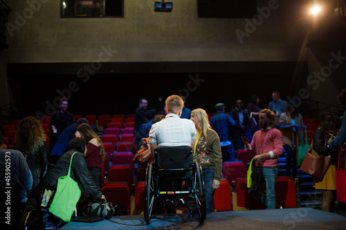 Speaker in wheelchair talking to conference audience © KOTO