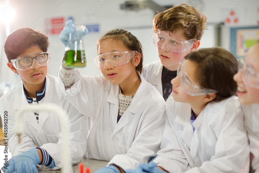 Curious students conducting scientific experiment, examining liquid in beaker in laboratory classroom Curious students conducting scientific experiment, examining liquid in beaker in laboratory classroom
